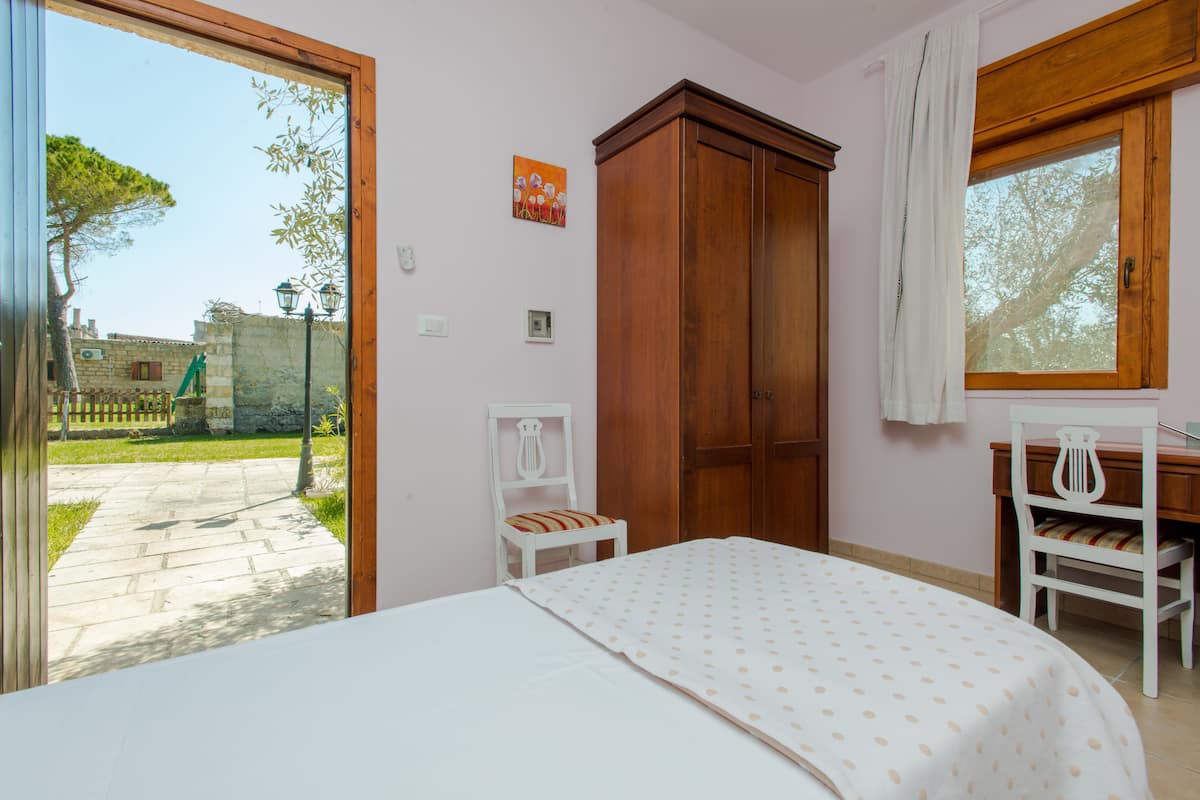Ein Schlafzimmer mit einem Bett, einem Holzschrank, einem Stuhl und einem Fenster.