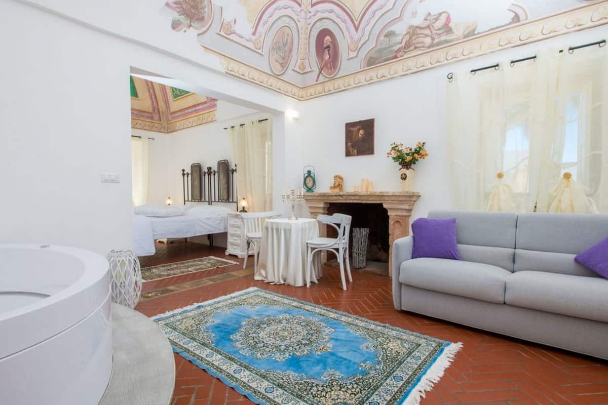 Ein geräumiges Wohnzimmer mit Kamin, einer Couch, einem Essbereich und einem großen Teppich.