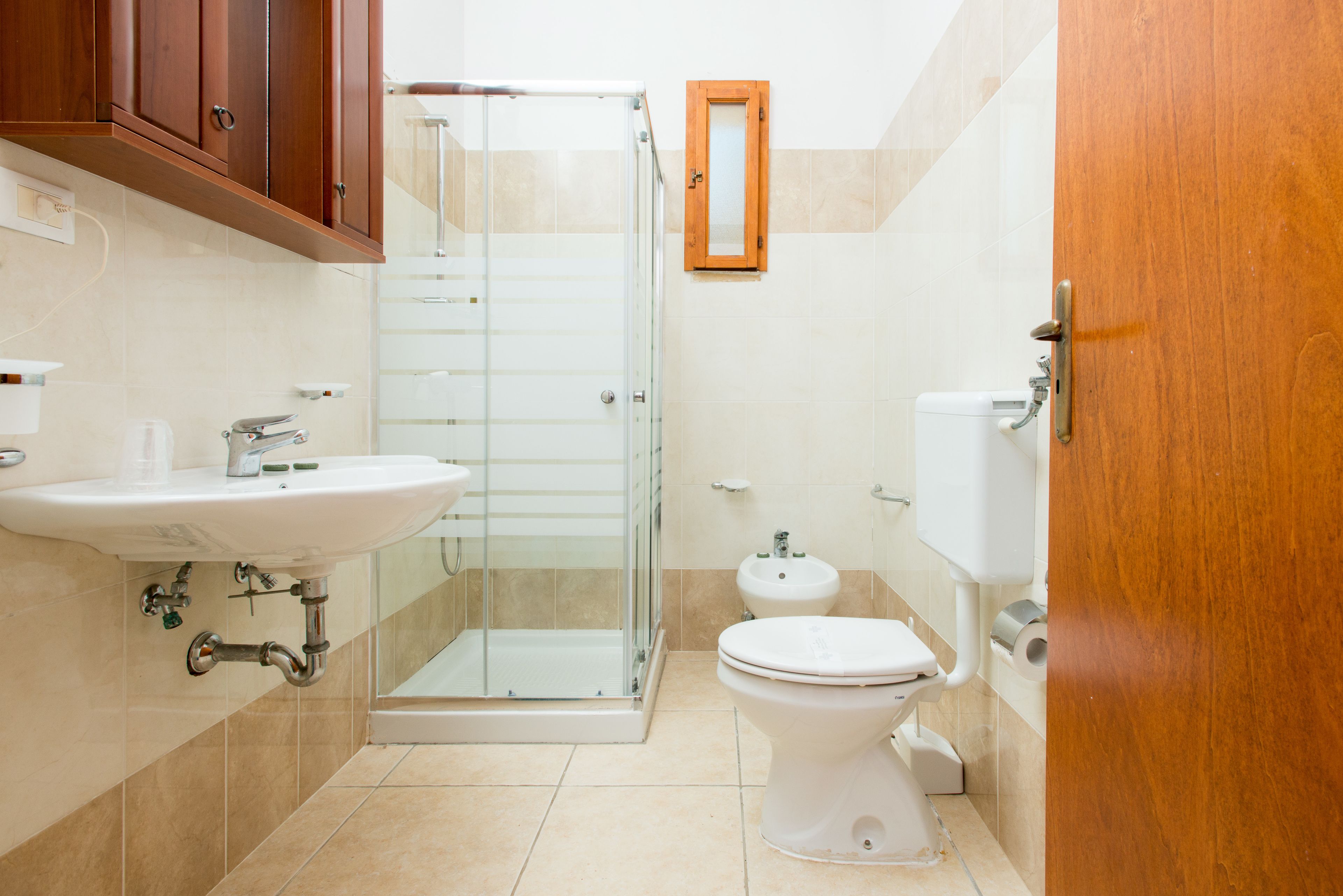 Un baño con ducha de vidrio, lavamanos, inodoro y bidé.