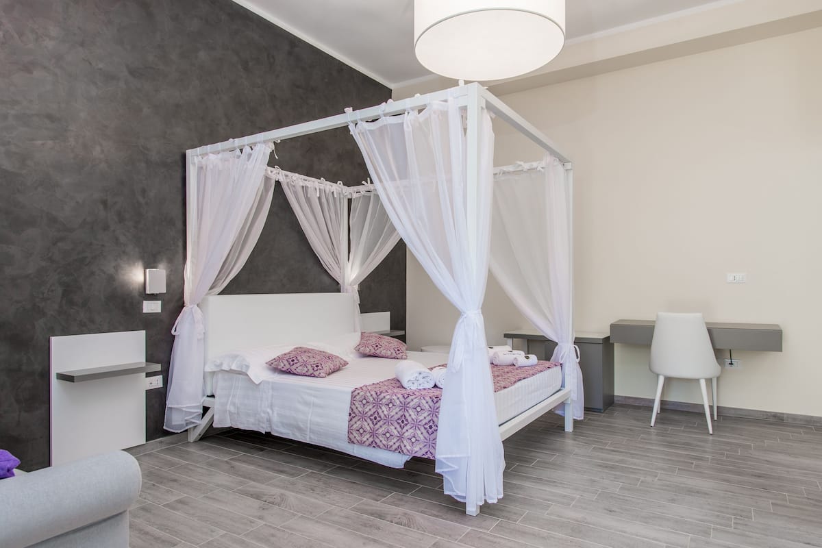 Ein modernes Schlafzimmer mit Himmelbett, Schreibtisch und Stuhl.