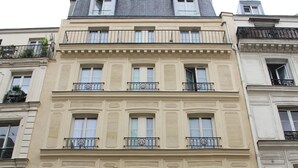 Um edifício de vários andares com estilo arquitetônico clássico, com varandas e grandes janelas.