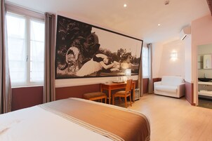 Habitación de hotel con una cama grande, un escritorio con una silla, un sofá y un cuadro de gran tamaño en la pared.