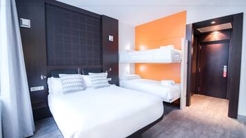 Een hotelkamer met een groot bed, een tweede stapelbed, een donker houten hoofdeinde en een oranje accentmuur.