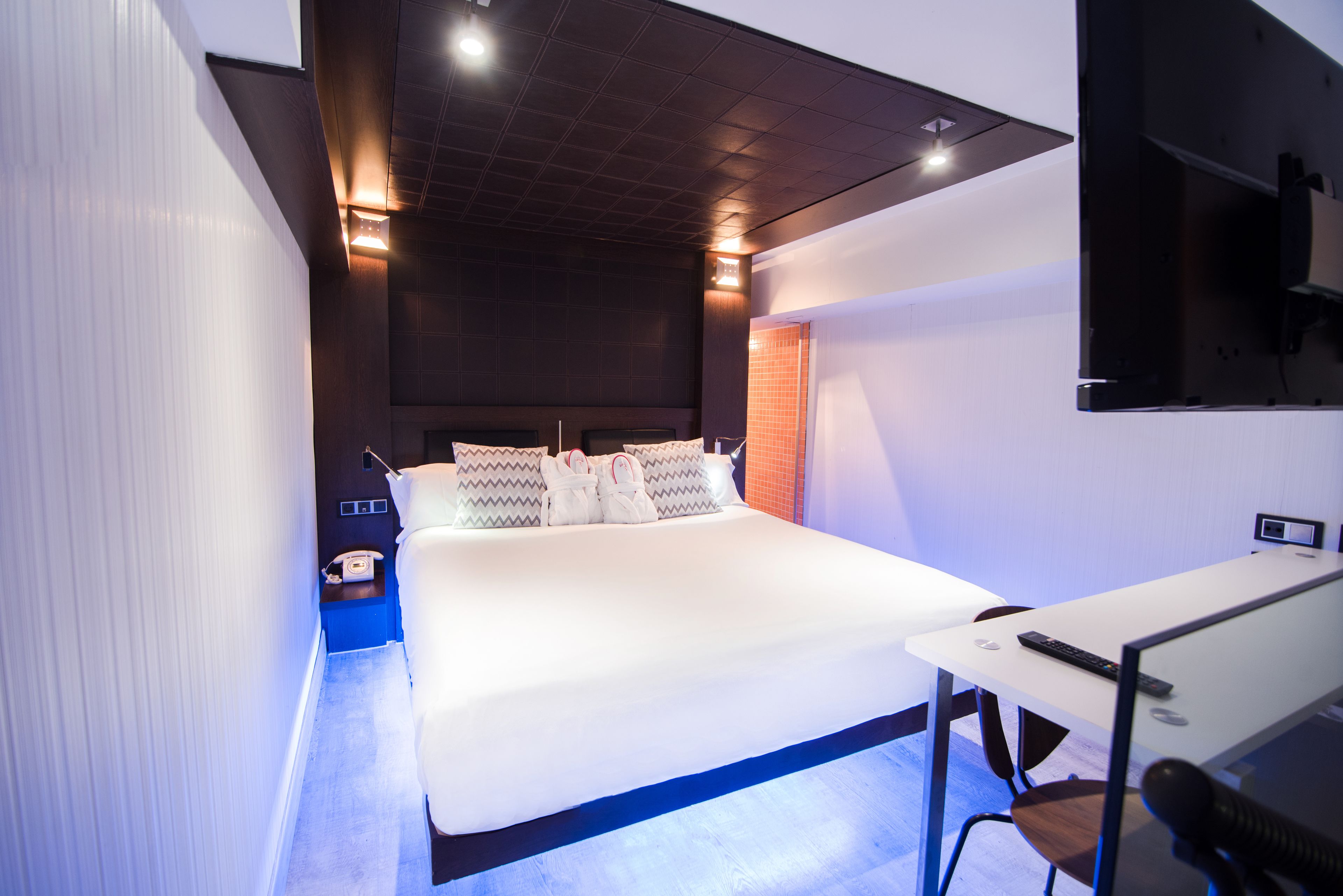 A modern hotel room with a large bed, a desk, and a television.
