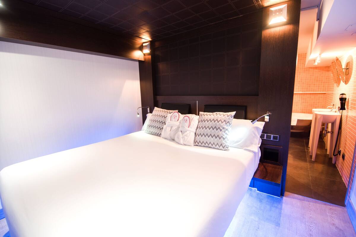 Een moderne hotelkamer met een groot bed, een inbouw bureau en een kleine badkamer.