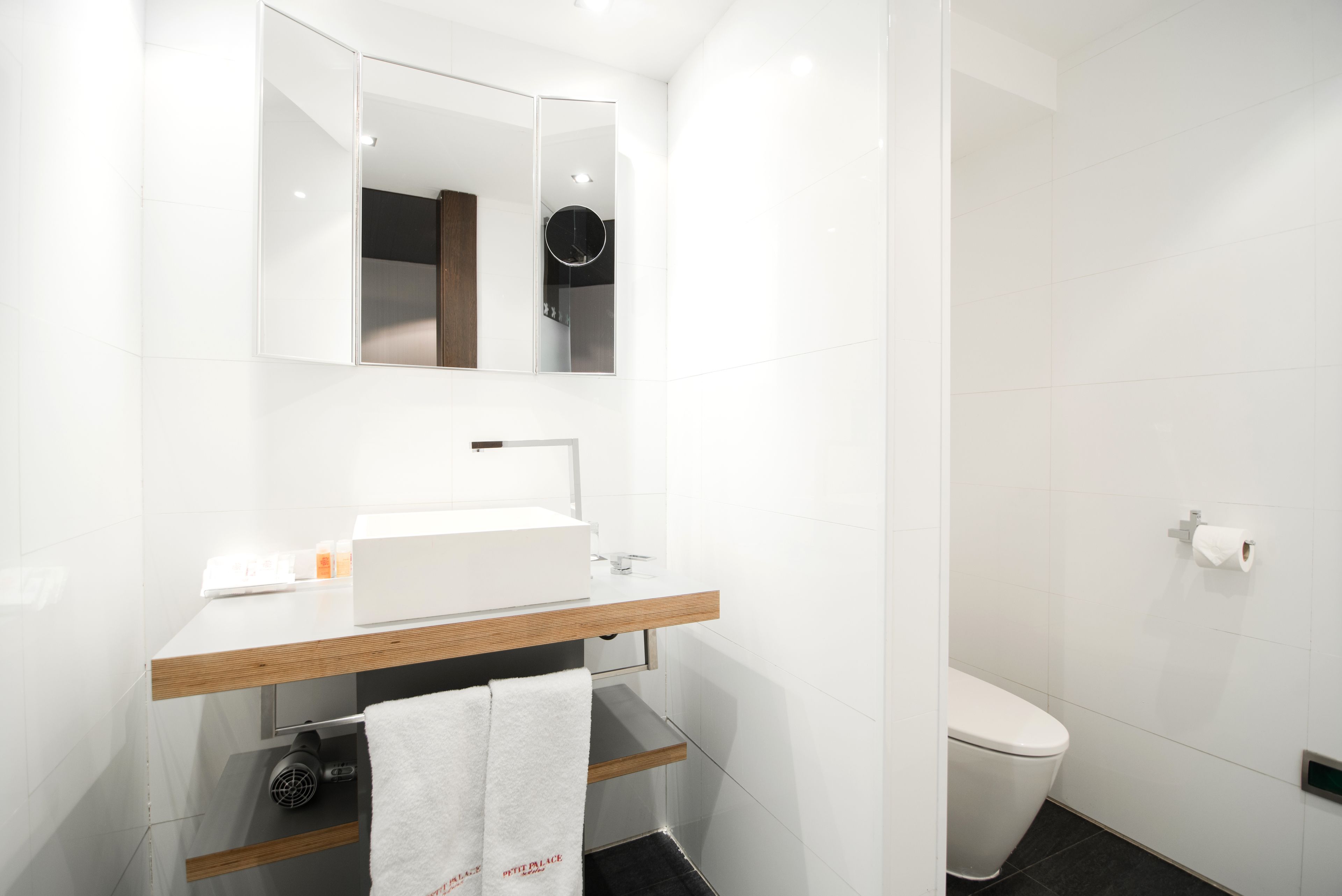 Un baño moderno con un lavamanos, espejo y inodoro blancos.