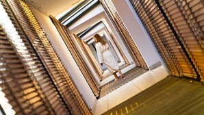 A corridor with a person walking towards a door. The corridor has patterned walls and a tiled floor.