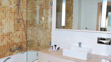 A bathroom with a bathtub, a shower, a sink, and a mirror.