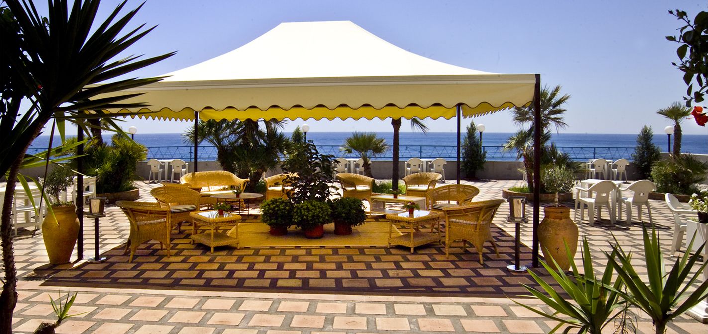 An outdoor patio with wicker furniture, a central table, and a large umbrella.