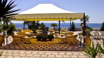 An outdoor patio with wicker furniture, a central table, and a large umbrella.