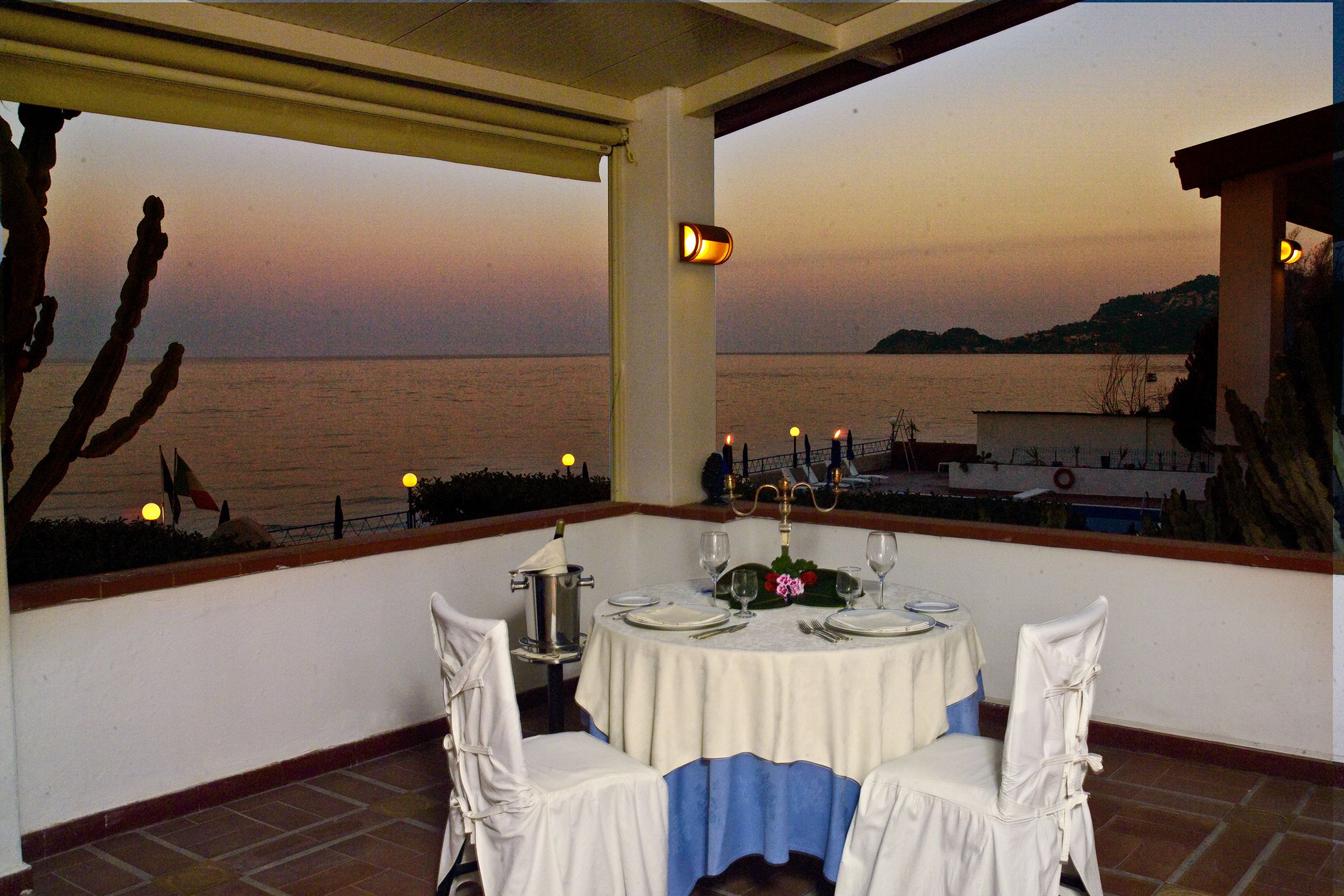 A table set for two with a view of the sea at sunset.