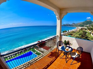 A balcony with a view of the sea, a pool, and a table with chairs. - Park Hotel Silemi (Letojanni)