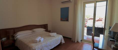 Habitación de hotel con cama, escritorio, silla y vistas al exterior.