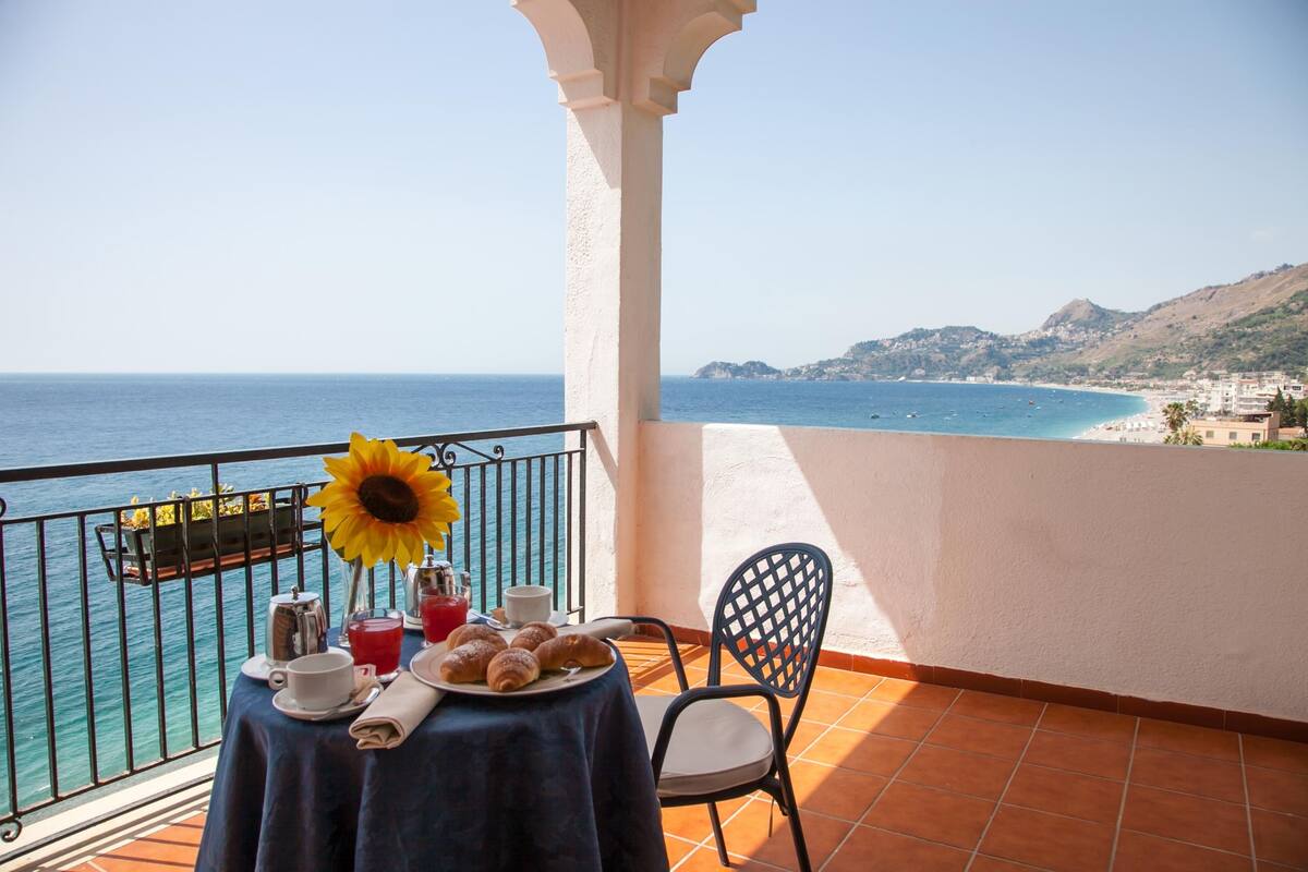 Ein Balkon mit Frühstückstisch und Blick auf die Küste.