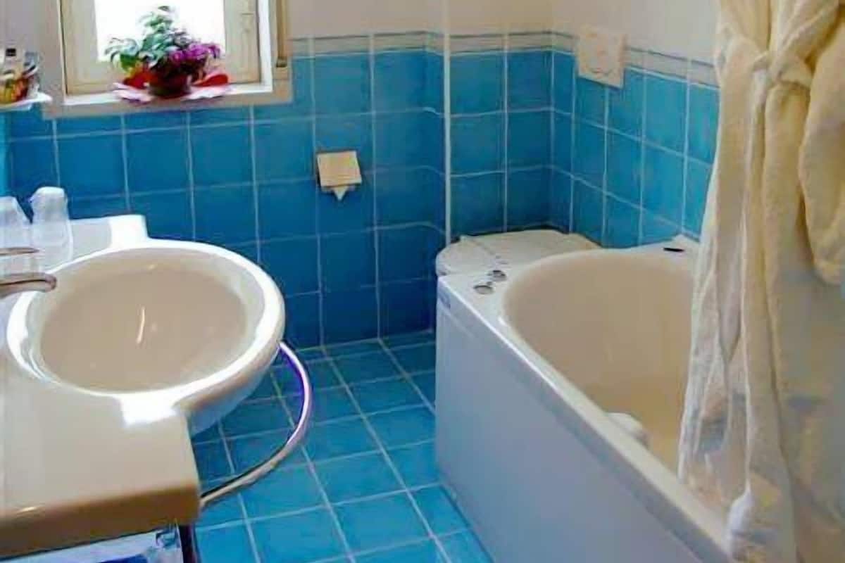 Ein Badezimmer mit Waschbecken, Badewanne und einem Fenster mit Jalousien.