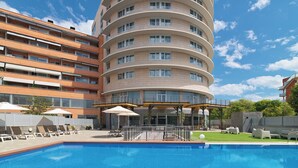 Een meerlaags hotel met een zwembad, terras en een overdekte patio.