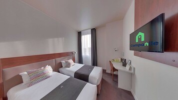 Habitación de hotel con dos camas, un escritorio, un televisor y una ventana con cortinas.