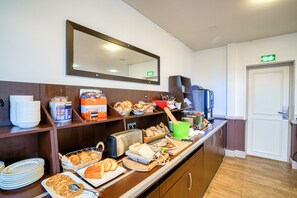 Un buffet de petit-déjeuner proposant divers aliments, un miroir et une porte portant un panneau indiquant la sortie de secours.