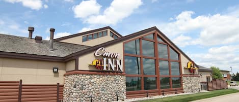 A hotel with a stone facade, large windows, and a prominent sign.