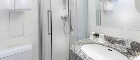 A modern bathroom with a glass-enclosed shower, a granite countertop sink, and a white bathtub.
