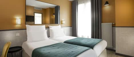 A hotel room with two beds, a chair, a mirror, and a window with curtains.