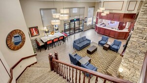 A spacious lobby with a staircase, a seating area with sofas and tables, a kitchen area, and a large mirror on the wall. - Comfort Inn Murray - Salt Lake City South (Murray)
