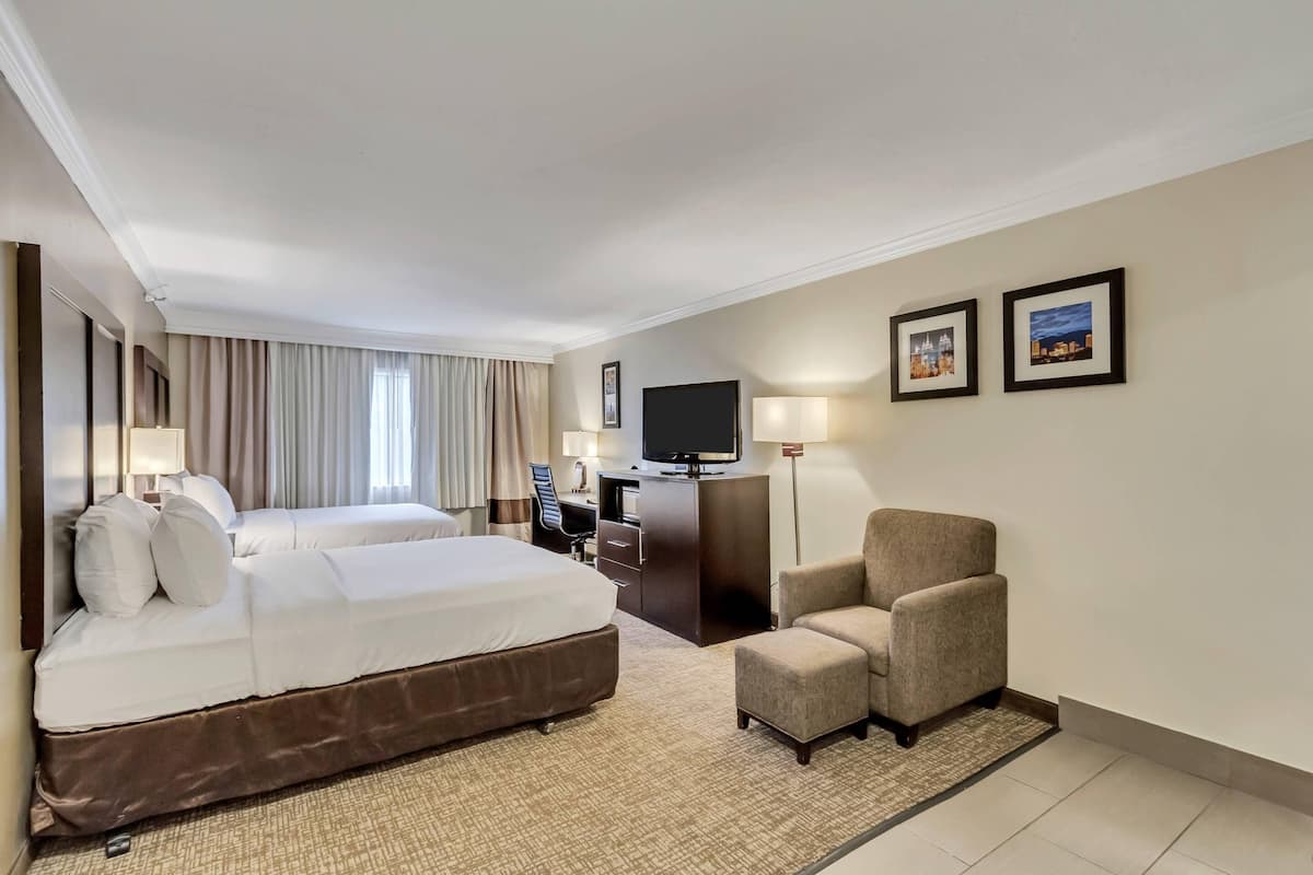 A hotel room with a large bed, a desk, a chair, and a television.