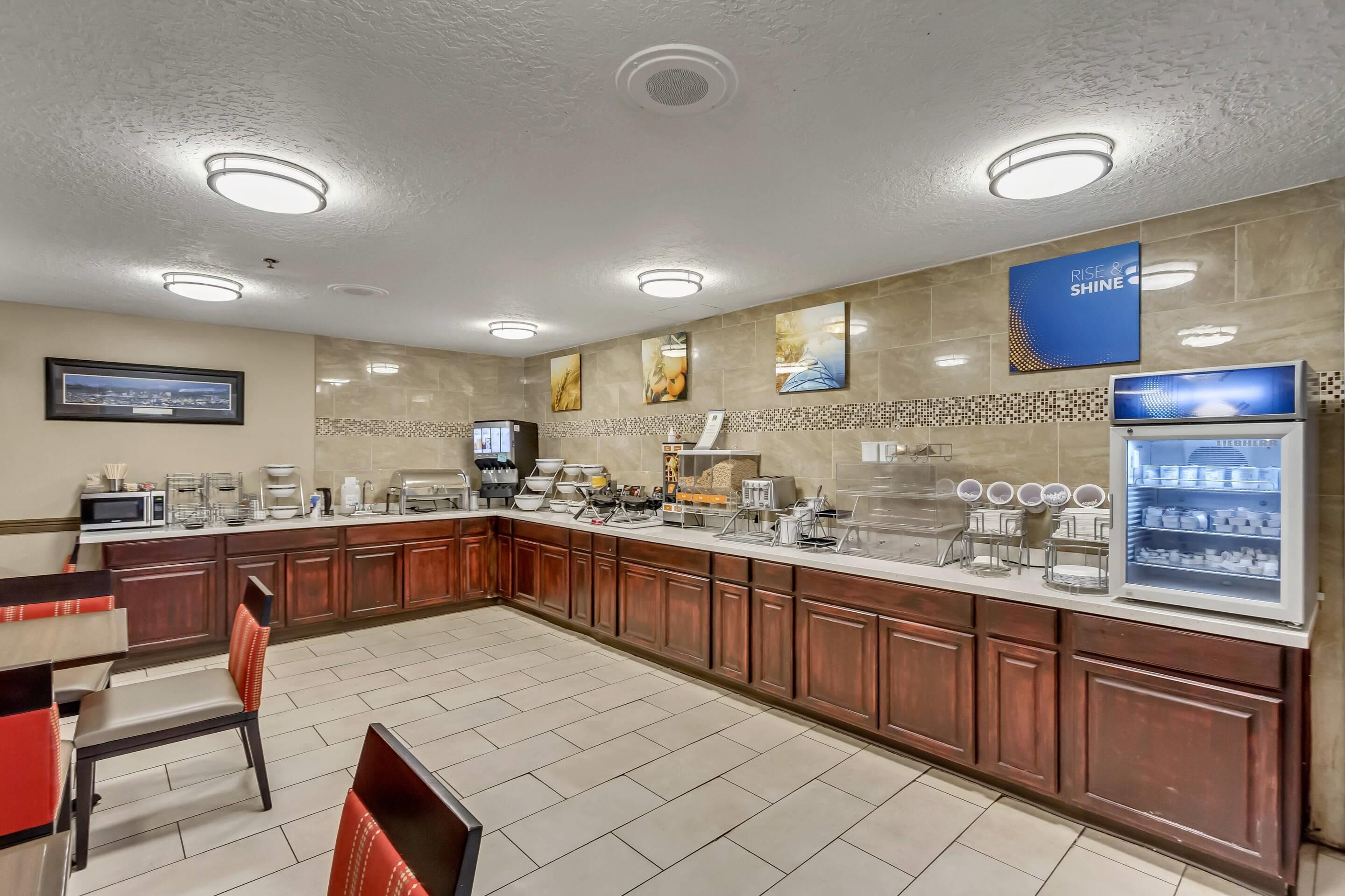 A modern kitchen with a long counter, various appliances, and a coffee station.