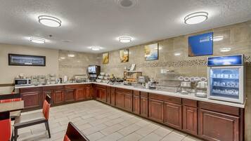 A modern kitchen with a long counter, various appliances, and a coffee station.