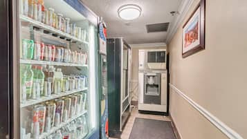 A hallway with a vending machine stocked with beverages and a water dispenser.