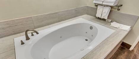 Un baño moderno con una bañera grande, un perchero con toallas dobladas y un cuadro en la pared.