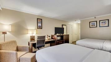 Una habitación de hotel con una cama, un escritorio con una silla, un televisor y una lámpara.