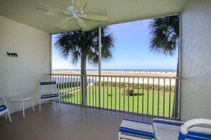 A balcony with a view of the beach, a ceiling fan, and a few chairs. - Gulfview Manor Resort (Fort Myers Beach)