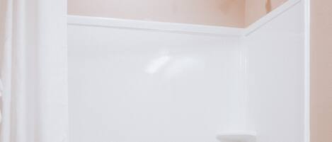 A bathroom with a shower curtain, a bathtub, a toilet, and wooden cabinets.