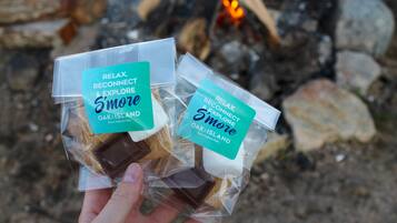 Een hand houdt twee porties snacks vast, gelabeld 'Relax, Reconnect & Explore S'more' van Oak Island.