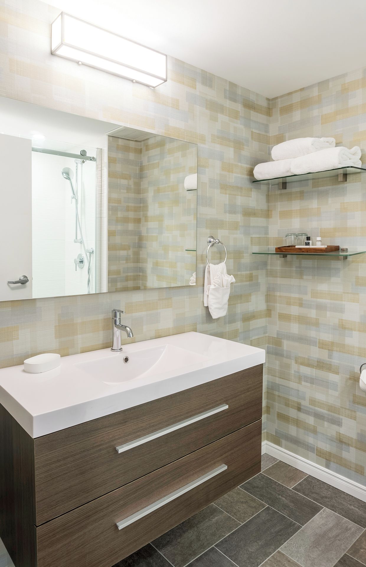 Un baño moderno con un espejo grande, un lavamanos blanco, una ducha y un perchero para toallas.