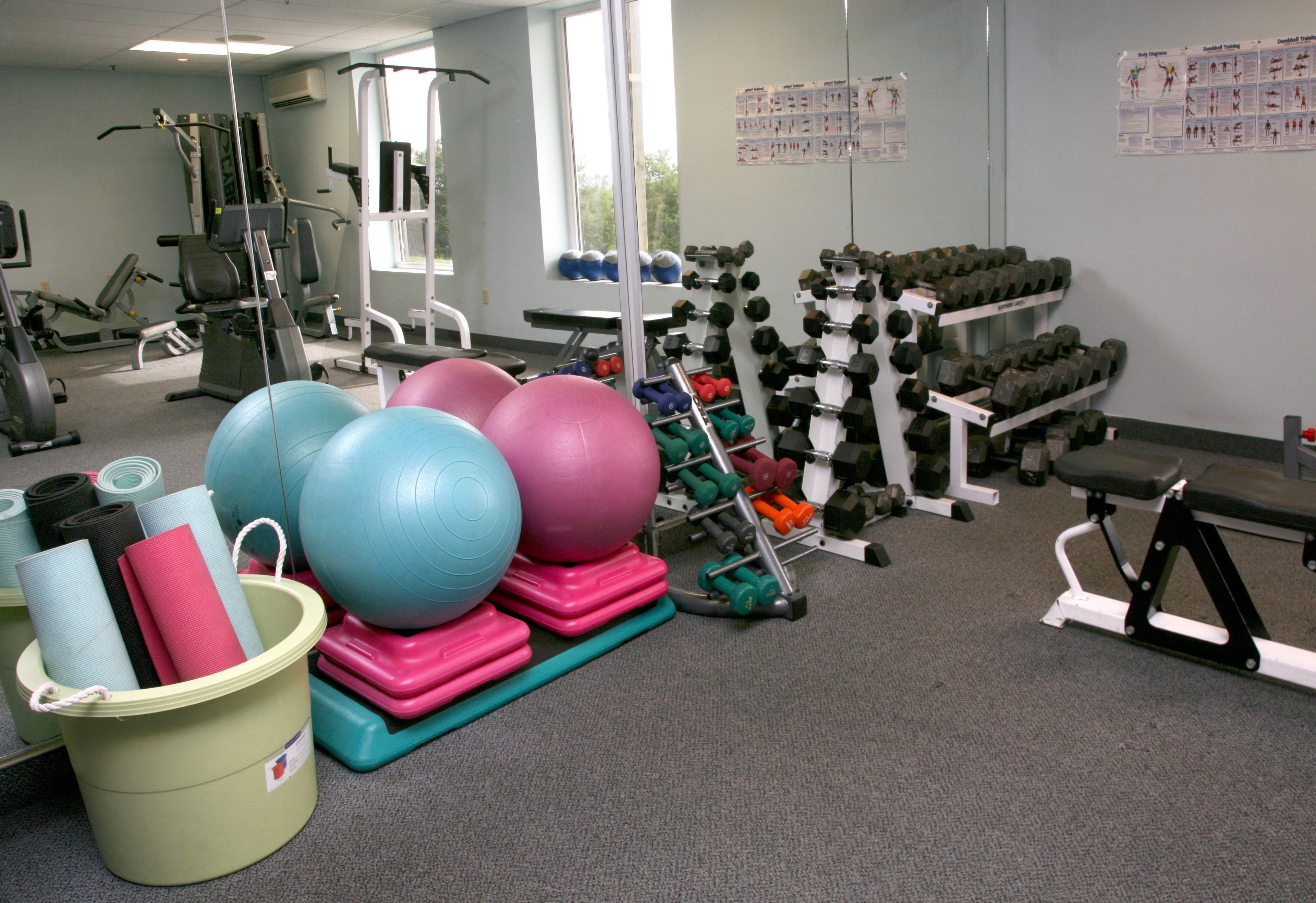 A gym with exercise equipment, yoga mats, and dumbbells.