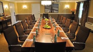 A conference room with a long wooden table, black chairs, and a chandelier.