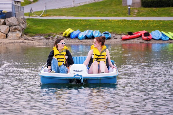 Two people in a small blue boat on calm water. - Oak Island Resort & Conference Centre (Western Shore)