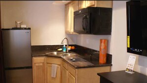 A compact kitchen with a refrigerator, microwave, sink, and a small countertop.