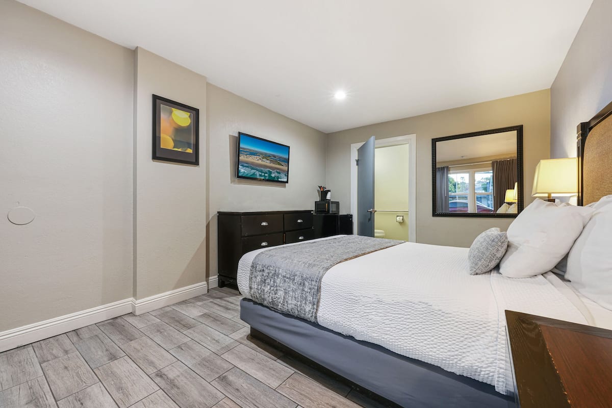 Un dormitorio con una cama grande, un aparador, un espejo y un cuadro en la pared.