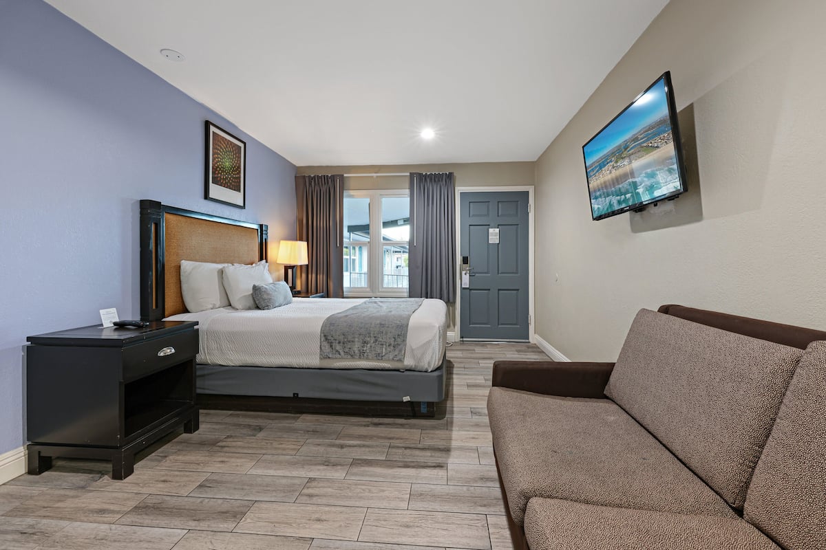 Un dormitorio con cama, mesita de noche, televisor y vistas al exterior.