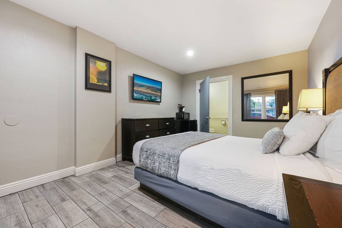 Un dormitorio con cama, cómoda, televisor y un cuadro en la pared.