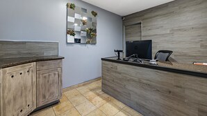 A reception area with a wooden reception desk, a computer, and a chair.