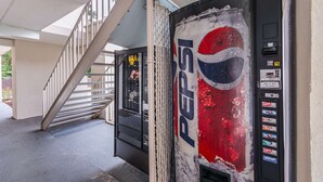 A Pepsi vending machine in a covered area with a staircase.