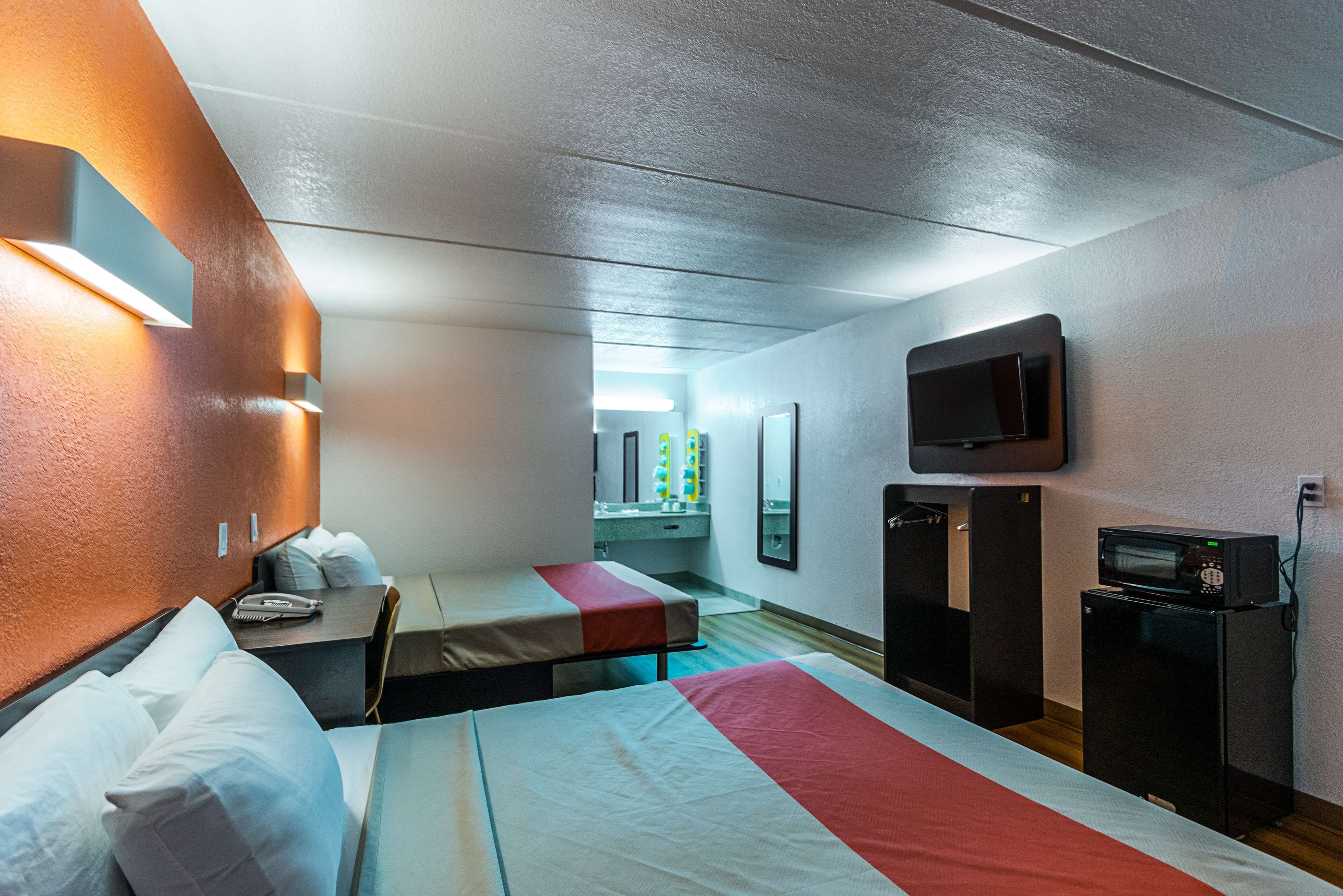 A hotel room with two beds, a TV, a microwave, and a small refrigerator.