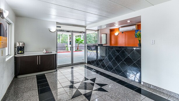 A modern lobby with a geometric tile floor, a coffee machine, and a glass door leading outside.