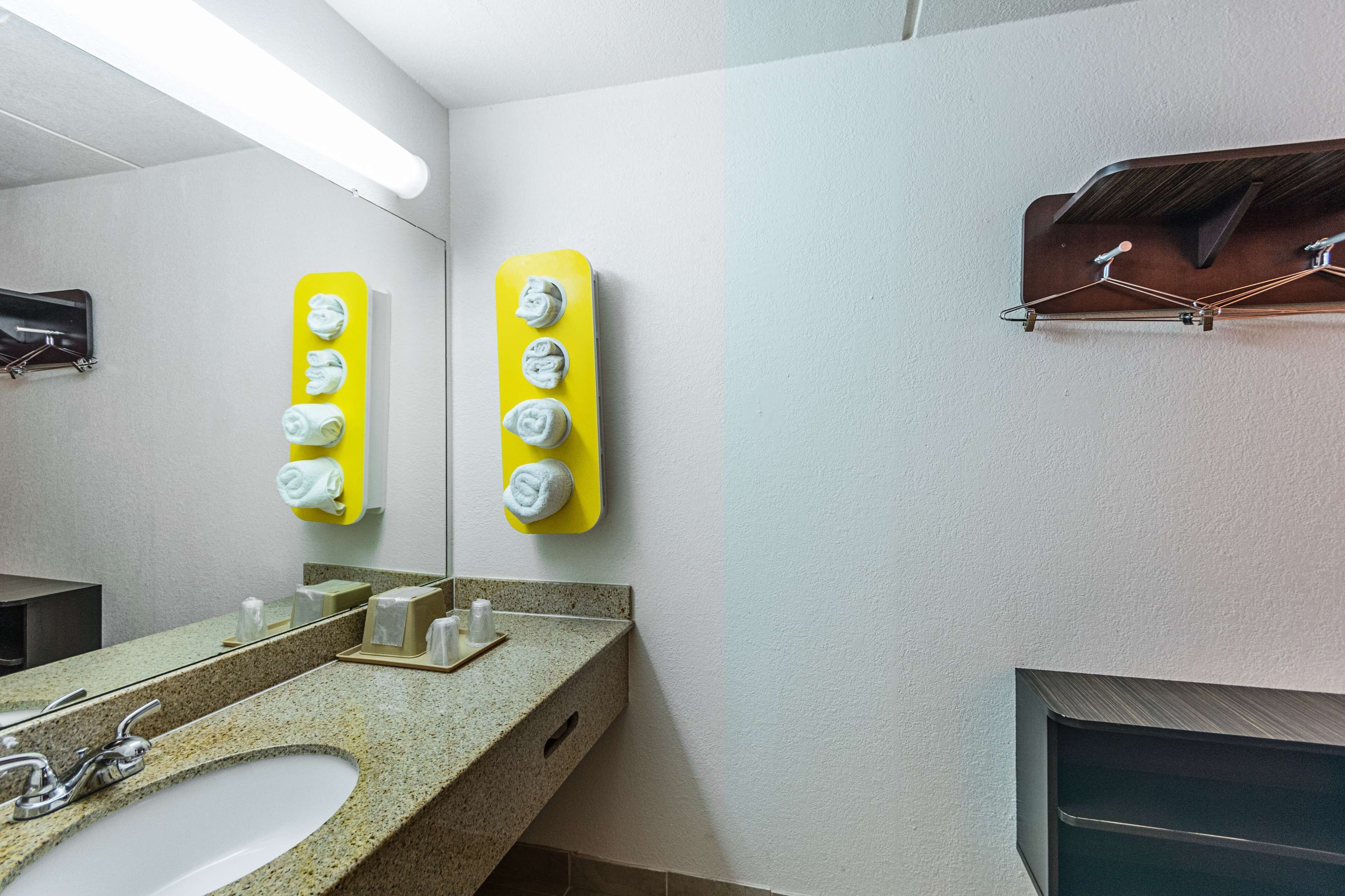 Un baño con lavamanos de granito, un espejo y dos dispensadores de toallas amarillos.