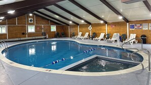 Una piscina interior con separadores de carril, una silla de socorrista y sillones de descanso alrededor de la piscina.