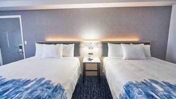Een hotelkamer met twee bedden, een nachtkastje en een wandlamp.